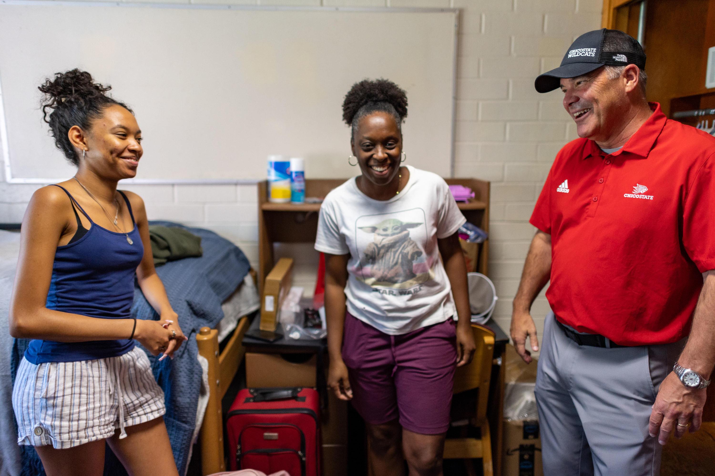 Mother, daughter and President perez sharing a laugh in the dorm room
