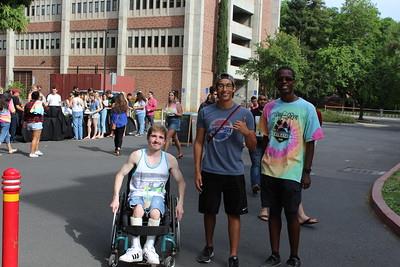 1 student in wheelchair with 2 students smiling at camera